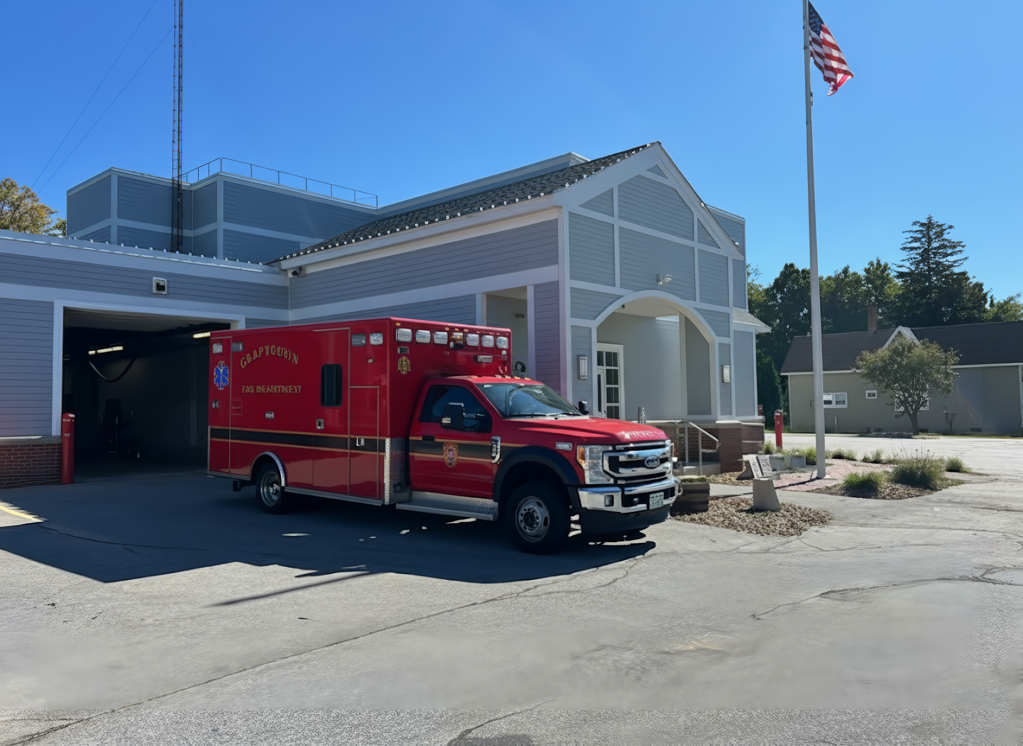 Ambulance parked in front of a modern fire station on a clear day.